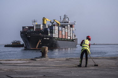 A port worker sweeps the dock as the Sima Pride, a container vessel, approaches the port of Berbera.