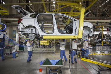 Workers operate on a vehicle assembly line at a General Motors joint venture factory.