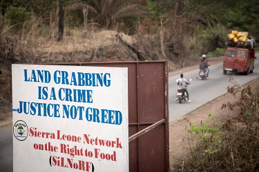 A billboard sign reads: 'Land Grabbing is a Crime...Justice not Greed'. Erected by a local NGO/human rights organisation in protest at the damaged caused by the failure of the Addax bioenergy plant.