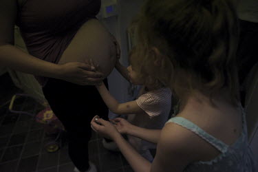 Bethany reaches up to touch her mother Lindsey who is pregnant with the family'ss third child. Although they live on social welfare benefits and find life a struggle, it is quite common for families t...