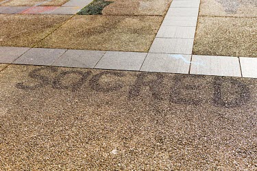 The word 'SACRED' on the ground at the site of the Aboriginal Tent Embassy, a semi-permanent assemblage where residing activists claim to represent the political rights of Aboriginal Australians. It i...