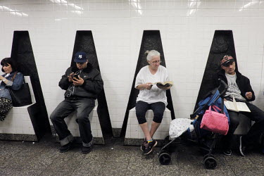 People read books and use mobile phones while waiting for a train in 161st Streetâ��Yankee Stadium New York City Subway station.