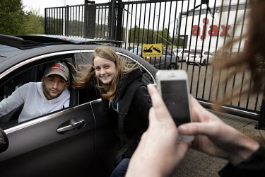 A fan has their picture taken with AFC Ajax football club striker Hakim Ziyech as he leaves the ground after training.