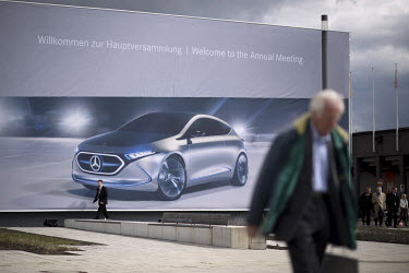 A shareholder walks near a billboard advertising Mercedes at a car exhibition during the Daimler AG company's annual shareholders meeting.