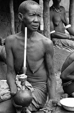 An Anuak woman smokes a water pipe.