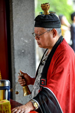 A Taoist priest rings a bell at the Bao An Temple. The temple was constructed in 1742 and inducted into UNESCO for cultural heritage conservation in 2003.