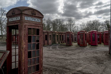 Old Post Office red phone kiosks stored in a muddy field at Unicorn Restorations, a company that renovates and sells disused street furniture.
