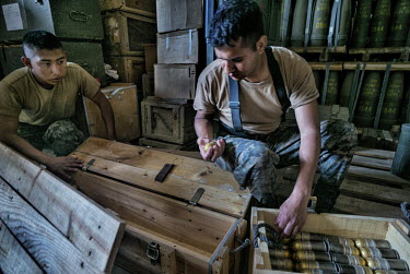 Soldiers sort through boxes of 40mm grenades in an ammunition store. A British NGO is assisting with the security of weapons and ammunition stores, providing training, fencing, locks and CCTV.
