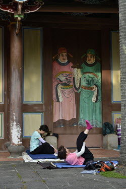 People exercising under the gaze of a pair of painted Door Gods, in Taipei's Botanical Garden.