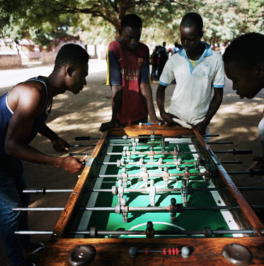 Youths playing table football while two students watching on.