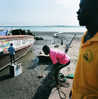 Boat owner Madane looks on as workers repair his boat which is used to transport cashew nuts from the island of Bolama to the capital.