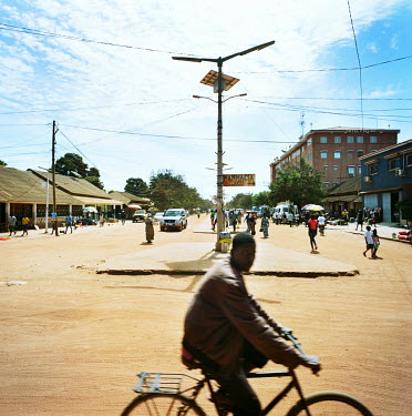 A man rides his bicycle along the main road in the town centre.