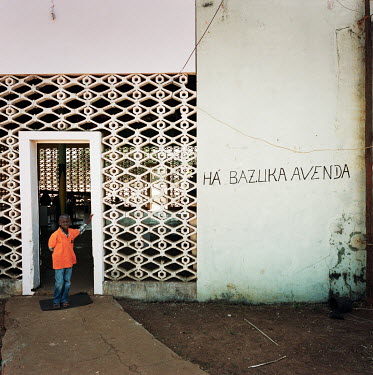 A boy stands at the entrance of a bar on the town's main road. (The graffiti on the wall reads: 'We sell Bazooka').