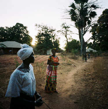Two women talking on a path that links the village to an area where the villagers gather for communal events.