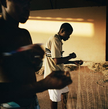 Fishermen repair their nets in a warehouse near Porto Bandim.