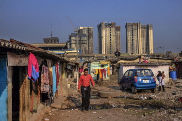 An area of low-rise slum buildings are in stark contrast to the skyscrapers of a residential development rising behind them.