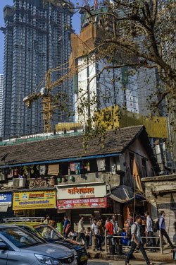 A row of small low rise businesses are dwarfed by skyscrapers rising behind in a development in the upmarket Worli district.