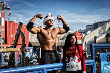 A bodybuilder shows his muscles to tourists at Muscle Beach.