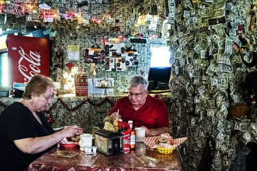 A couple having lunch in the Boatman hotel where the walls have been decorated with dollar bills stuck on by tourists.