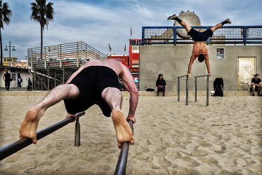 People using exercise and gymnastics equipment at Muscle Beach.