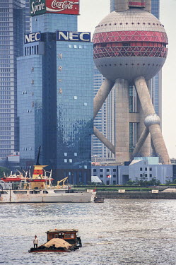 A barge crossing the Huangpu River with Pudong District and the landmark Oriental Pearl Radio and TV Tower in distance.