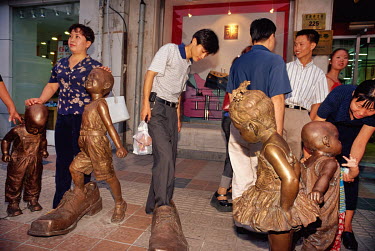 Visitors marvel at a display of sculptures of small children in Panjiayuan market.