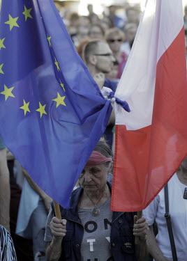 A protester carries an EU and a Polish flag at a rally in front of the Supreme Court to protest against the unconstitutional reform carried through parliament by the ruling Law and Justice party (PiS)...