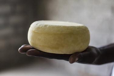 A worker at a cheese factory near Katale village displays a wheel of young Masisi gouda.
