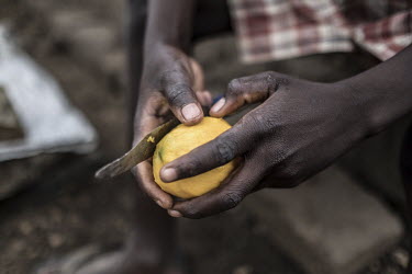 A young refugee peels a mango in Bidibidi refugee camp.
