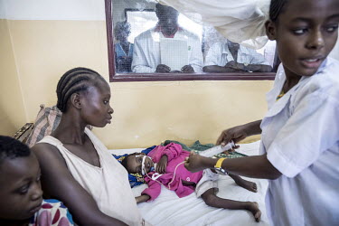 A health worker feeds a malnourished infant via a tube through her nose at a rural health centre.