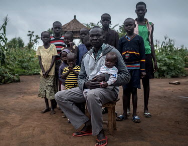 Malis Joseph, a refugee from South Sudan, with his youngest daughter and some of his 21 children, in Bidibidi refugee camp. He supports three wives, 21 of his own children and five unaccompanied nephe...