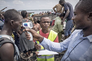 A health uses a non-contact forehead infrared thermometer to screen passengers for Ebola symptoms as they disembark from one of the many boats that ply the Congo River.