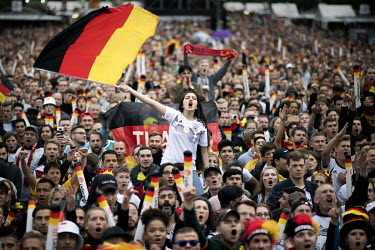 A woman waving the national flag stands out from a crowd watching Germany play Sweden at the FIFA 2018 World Cup on a giant screen erected on the Fanmeile (fan mile), Strasse des 17. Juni.