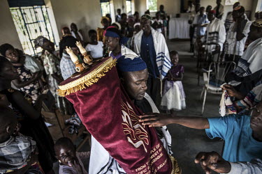 Members of the congregation reach out to touch the Torah in the Namanyoni synagogue. Over the years Jewish visitors have donated Hebrew scripts, skull caps, Menorah candles and other equipment to the...