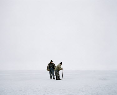 A man uses a rod to make a hole in the ice through which he will be able to fish the waters of the Aral Sea.