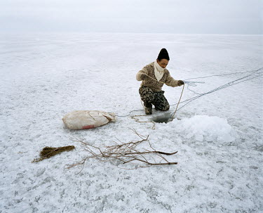 Zhakslik secures his fishing nets, dropped through ice holes into the waters of the Aral Sea beneath, for the night. He will return the following day to retrieve his catch.