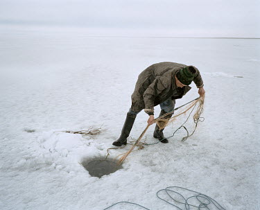 Fisherman Ertaz Akhkoshkarov, pulls in his net, dropped through an ice hole into the waters of the Aral Sea beneath.