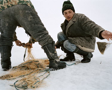 Fishermen retrieve fish caught in their nets in the frozen waters of the Aral Sea.