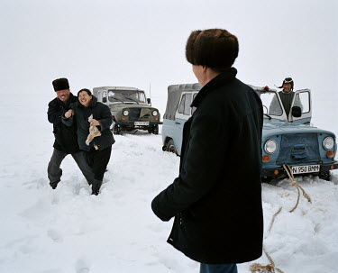 A man and a woman laugh as they travel by convoy across the frozen steppe.