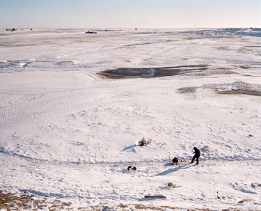 A man drags a sled in what once formed the Aralsk port that served ships on the Aral Sea, now more than 100 kms away.