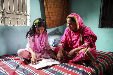 Former textile worker Sabina Khatun (25) helping her eldest daughter Sumaiya (10) with homework.