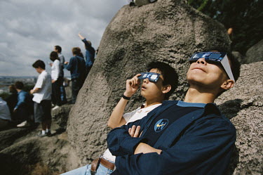 Youths in Belleville Park look at the eclipse of the sun through special protective glasses.