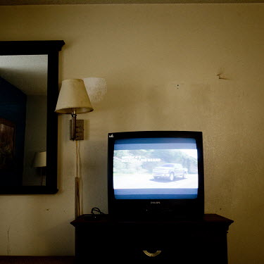 A commercial for a car company plays on a television in a motel room.