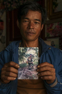 Sreng Oun (40) a farmer holds a photograph of himself as a deminer for HALO in Ou Pok village.