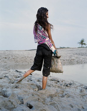 A girl collects shrimp in a net. Such activity is begining to replace traditional rice farming which has become increasingly difficult due to rising sea levels causing salinisation of the ground water...