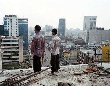 Two men look over the city from a part-built building.