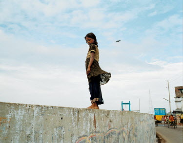 A girl stands on the concrete wall that forms part of the flood protection for the city.