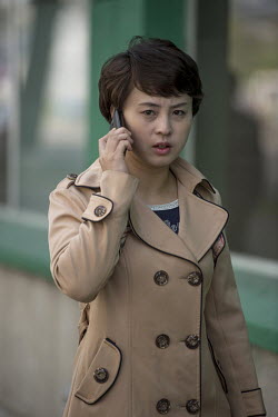 A fashionable young woman makes a call on her mobile phone as she walks in the city.