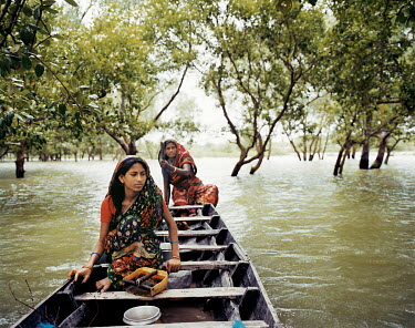 Fatema and Mojida return home in a boat through the mangroves after travelling to find potable water. Increased salinisation has reduced the availablility of fresh water in the region.