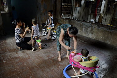 Women feed their young children who are playing in a corridor in the former Le President Hotel which was used by the American military in the 1960s up until the evacuation of 1975. Many of the rooms i...